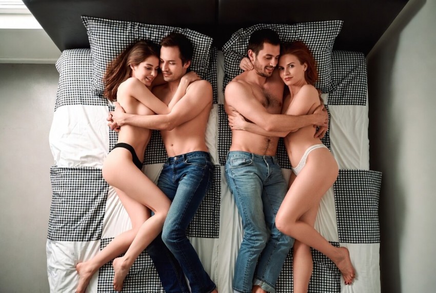 Zwei Paare liegen eng umschlungen auf einem Bett &ndash; sinnliches Bild zum Thema Swinger Kontakte Schweiz